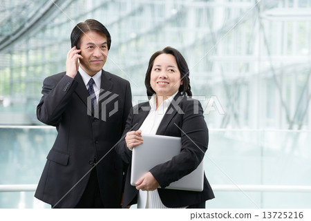 一個中年男人和一個女人穿著一台個人電腦在現代建築中的西裝 13725216