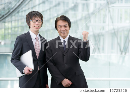 A man in a suit standing with a laptop computer in a modern building 13725226