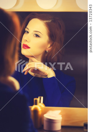 Portrait of a beautiful woman as applying makeup near a mirror 13728343