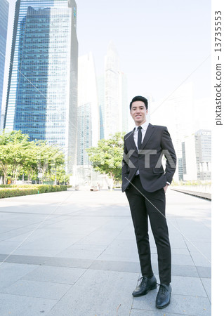A smiling business man standing in front of building 13735553