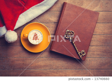 Cappuccino with key and book on wooden table. 13740660