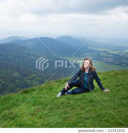 Girl sitting on the slope of volcano in Auvergne 13741050