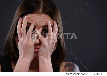Teenage girl frightened looking through fingers Teenage girl frightened looking through fingers 13746160