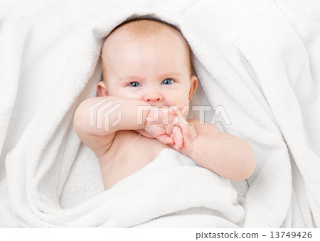 Cute baby lying on white towel and sucking own hand Cute baby lying on white towel and sucking own hand 13749426