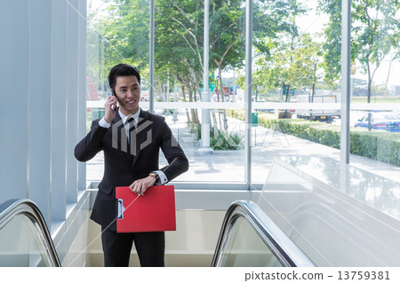 Asian man holding file on escalator 13759381