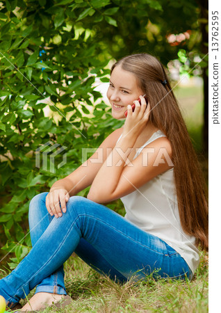 Teenage girl with a mobile phone near a tree Teenage girl with a mobile phone near a tree 13762595