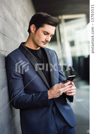 Attractive young businessman on the phone in an office building Attractive young businessman on the phone in an office building 13763531