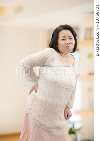 A middle-aged woman in casual wear, standing indoors A middle-aged woman in casual wear, standing indoors 13766833