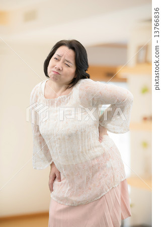 A middle-aged woman in casual wear, standing indoors 13766836