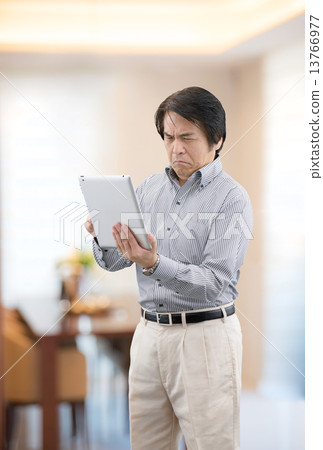 在家操作片劑的便衣的中年人居住 13766977