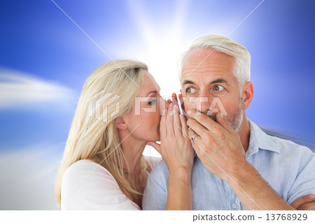 Composite image of woman whispering a secret to husband Composite image of woman whispering a secret to husband 13768929