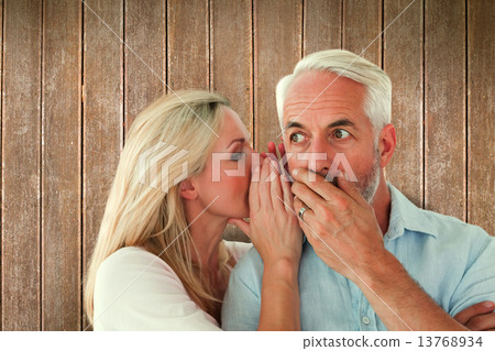 Composite image of woman whispering a secret to husband Composite image of woman whispering a secret to husband 13768934