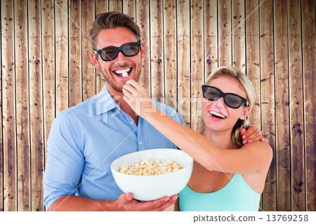Composite image of happy young couple wearing 3d glasses eating Composite image of happy young couple wearing 3d glasses eating 13769258