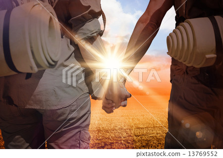 Composite image of hitch hiking couple standing holding hands on 13769552
