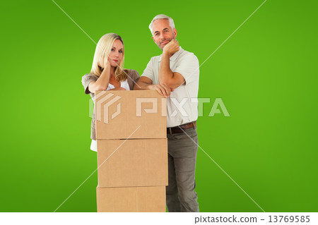 Composite image of happy couple leaning on pile of moving boxes Composite image of happy couple leaning on pile of moving boxes 13769585