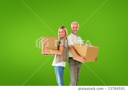 Composite image of happy couple holding moving boxes Composite image of happy couple holding moving boxes 13769591