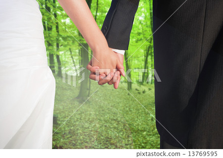 Composite image of close up of cute young newlyweds holding thei Composite image of close up of cute young newlyweds holding thei 13769595