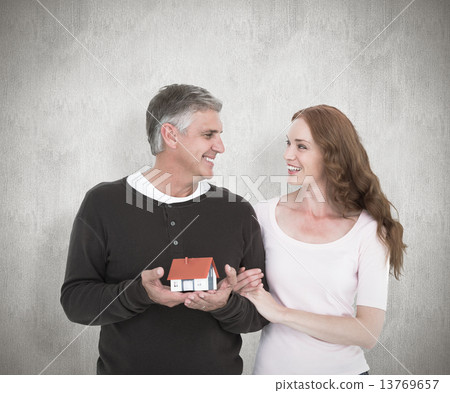 Composite image of casual couple holding small house Composite image of casual couple holding small house 13769657