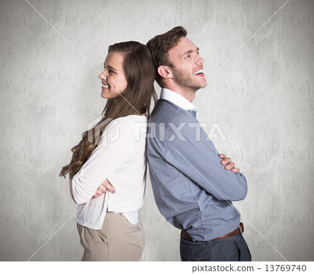 Composite image of happy young couple standing back to back Composite image of happy young couple standing back to back 13769740