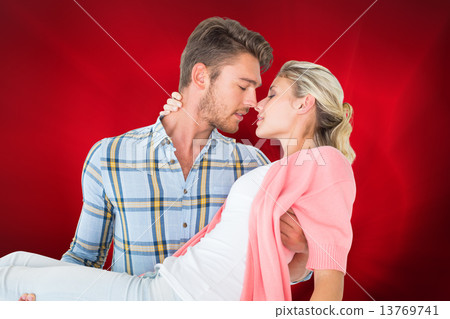 Composite image of handsome man picking up and hugging his girlf 13769741