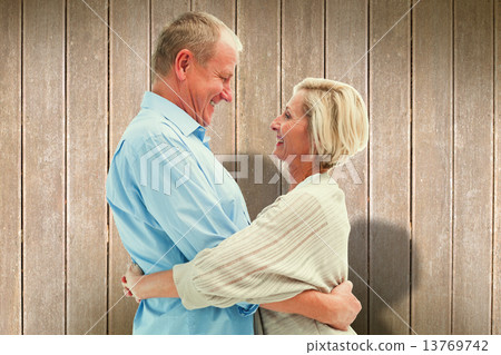 Composite image of happy mature couple hugging and smiling Composite image of happy mature couple hugging and smiling 13769742