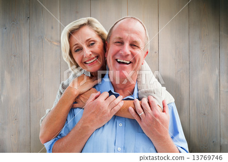 Composite image of happy mature couple embracing smiling at came 13769746