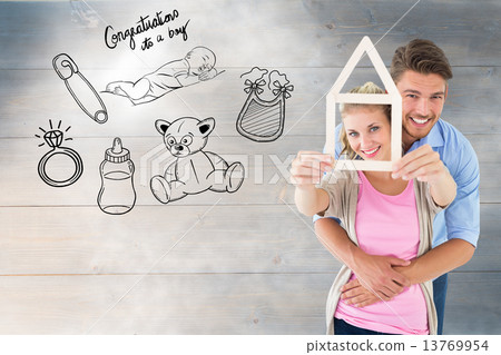 Composite image of young couple hugging and holding house outlin 13769954