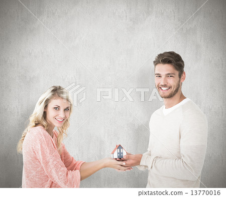 Composite image of attractive couple holding miniature house mod Composite image of attractive couple holding miniature house mod 13770016