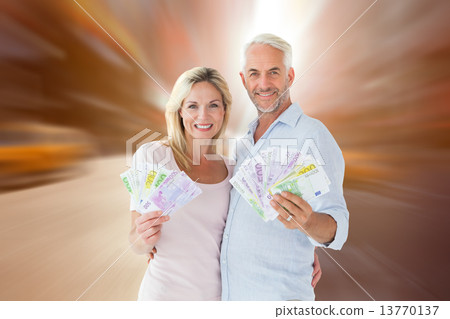 Composite image of happy couple flashing their cash Composite image of happy couple flashing their cash 13770137