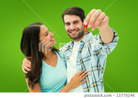 Composite image of happy young couple showing new house key Composite image of happy young couple showing new house key 13770146