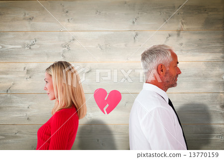 Composite image of couple not talking with broken heart between Composite image of couple not talking with broken heart between 13770159