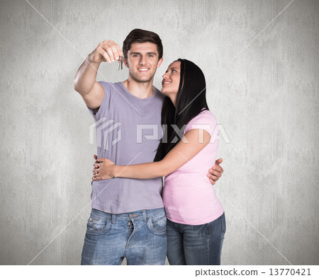 Composite image of young couple showing keys to house 13770421