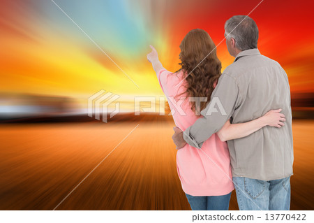 Composite image of casual couple standing arms around Composite image of casual couple standing arms around 13770422