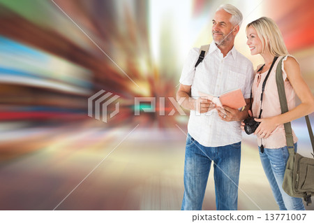 Composite image of happy tourist couple using the guidebook 13771007
