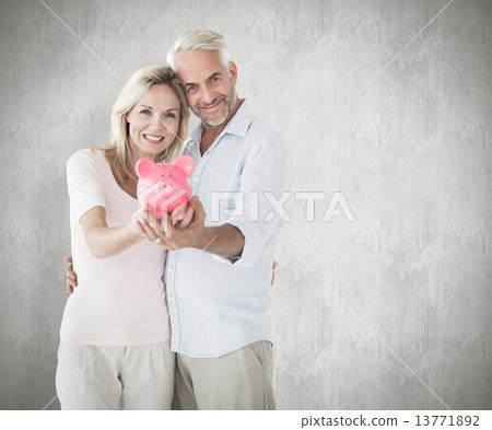 Composite image of happy couple showing their piggy bank Composite image of happy couple showing their piggy bank 13771892