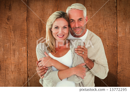 Composite image of happy couple standing and hugging 13772295