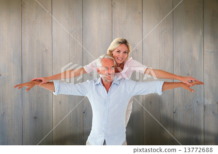 Composite image of smiling couple posing with arms out Composite image of smiling couple posing with arms out 13772688
