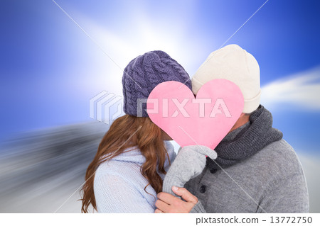 Composite image of couple in warm clothing holding heart Composite image of couple in warm clothing holding heart 13772750