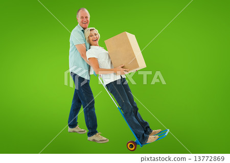 Composite image of fun older couple holding moving boxes Composite image of fun older couple holding moving boxes 13772869