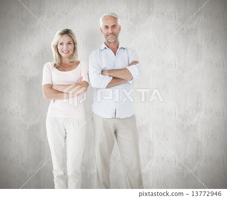 Composite image of smiling couple standing with arms crossed 13772946