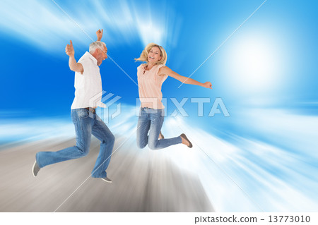 Composite image of excited couple cheering and jumping Composite image of excited couple cheering and jumping 13773010
