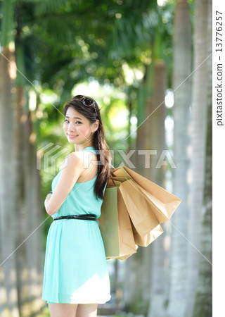 One young chinese woman shopaholic along promenade 13776257