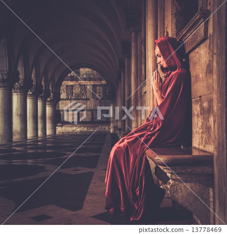 Woman in red cloak praying alone 13778469