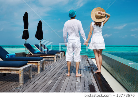 Couple on a beach jetty at Maldives Couple on a beach jetty at Maldives 13778676
