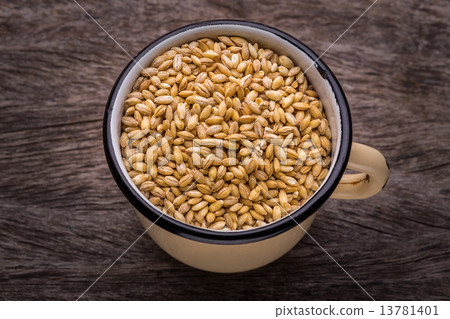 图库照片 rustic bowl with grains of wheat on wooden texture.