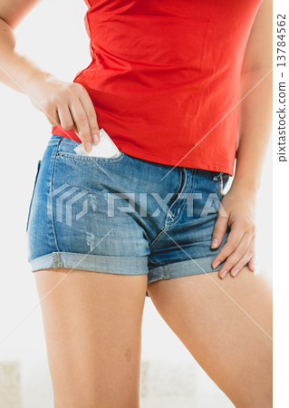 slim woman taking condom out of jeans shorts 13784562