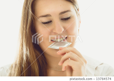 toned portrait of sexy brunette woman holding condom 13784574