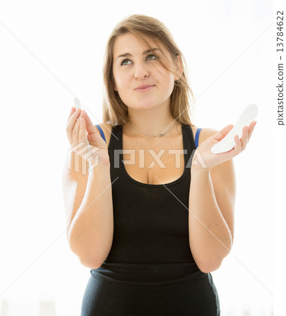 cute brunette woman choosing between menstrual pad and tampon cute brunette woman choosing between menstrual pad and tampon 13784622
