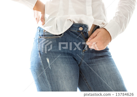 slim woman in white shirt unbuttoning blue jeans 13784626