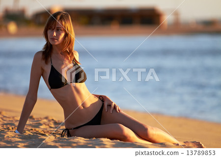 Young woman in bikini posing on sea coast Young woman in bikini posing on sea coast 13789853